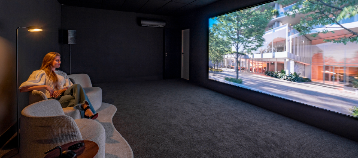 Sala de experiência no showroom do D/Sense onde os visitantes assistem a um vídeo sobre o projeto. O espaço conta com poltronas e uma tela grande, proporcionando uma apresentação informativa do empreendimento.