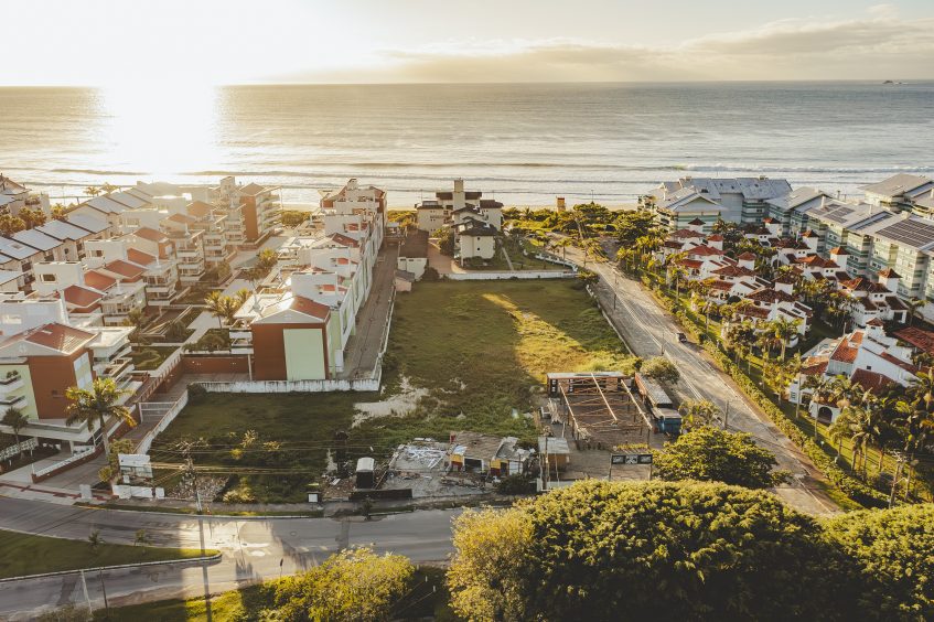 na imagem temos uma visão bem ampla onde mostra um empreendimento à beira-mar em Florianópolis, nessa imagem conseguimos ver o complexo de apartamentos bem organizados e distribuidos com uma visão do mar ao fundo.

