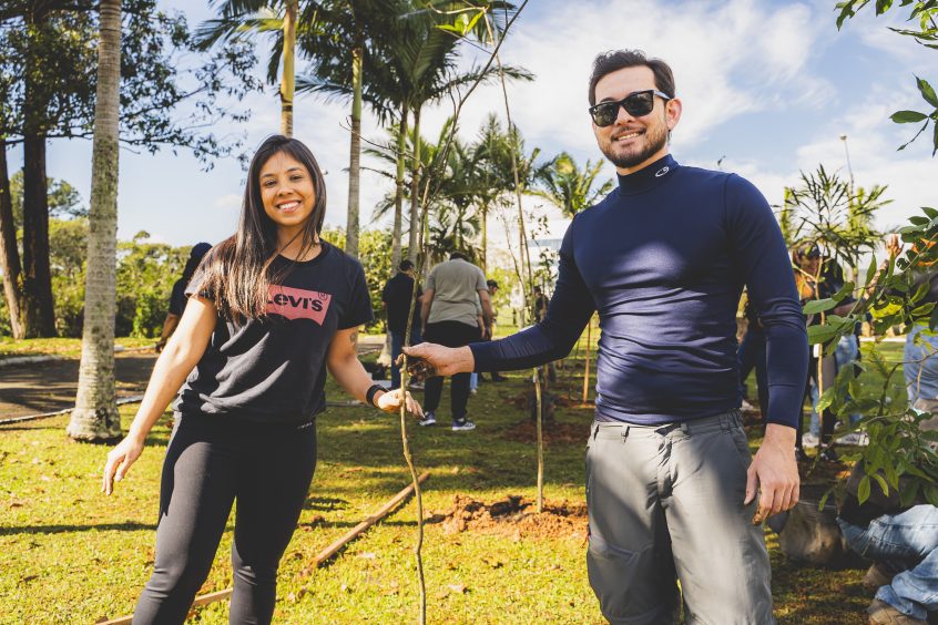 casal sorrindo para a foto segurando uma árvore recém plantada numa ação de plantio de mudas nativas em Florianópolis